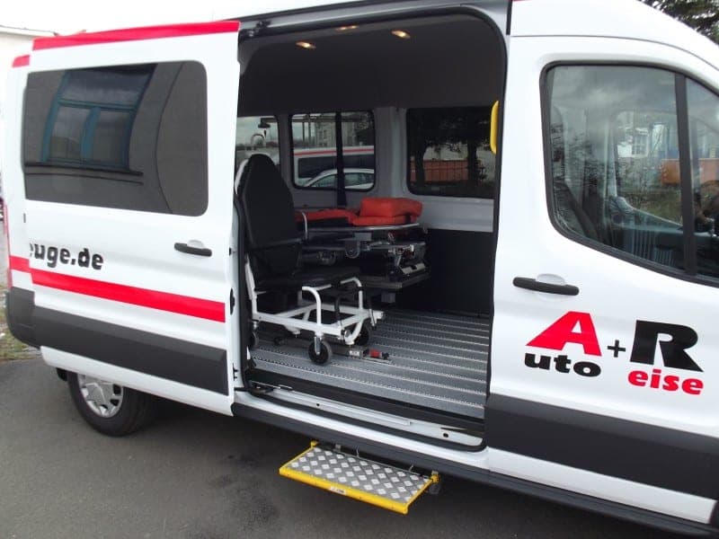 Geöffnete Schiebetür eines Ford Transit: im Innenraum eine Fahrtrage und ein Tragestuhl, ausgefahrene Trittstufe